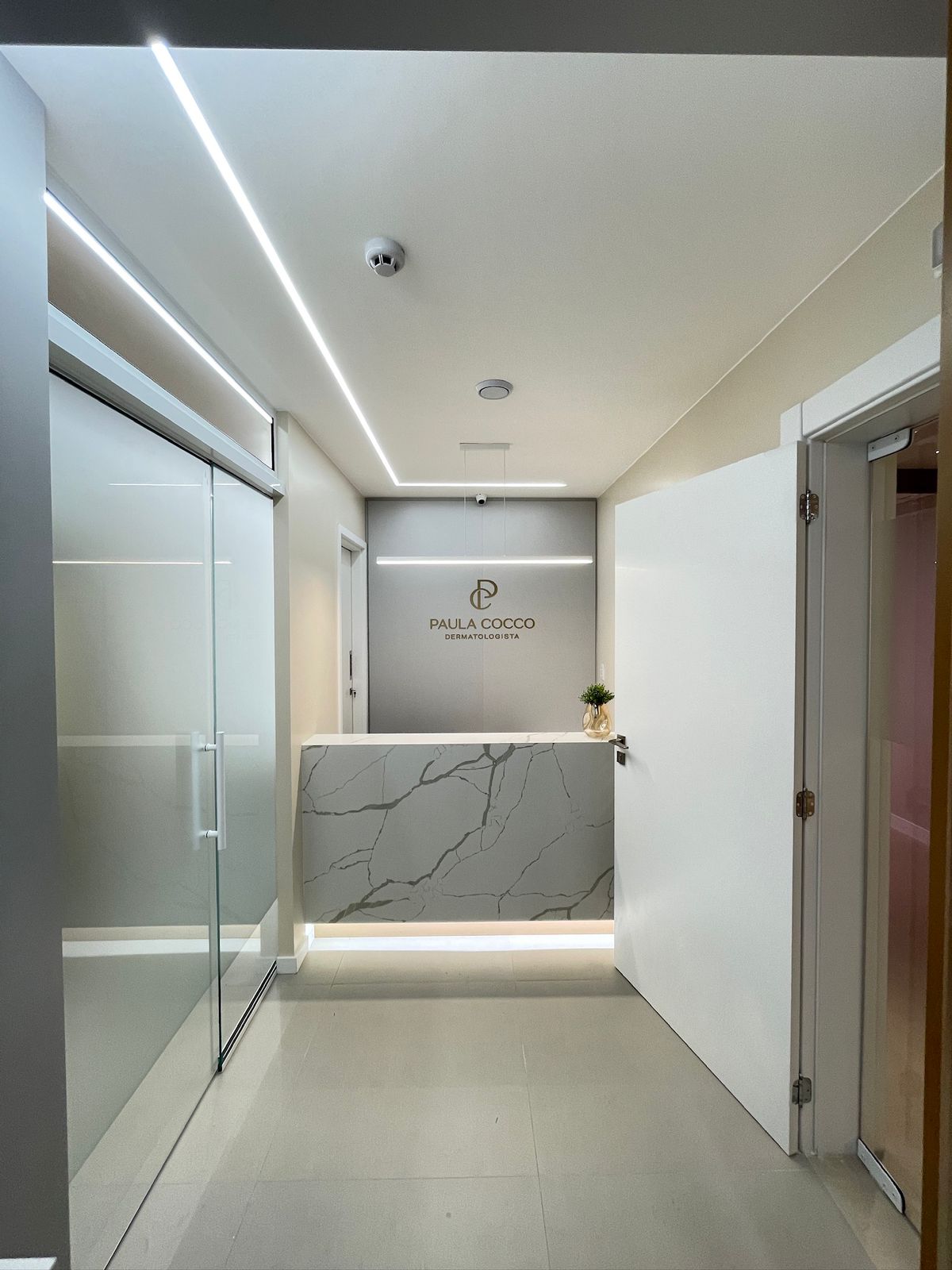 Recepção de clínica dermatologista com bancada em mármore — ATKA Arquitetura